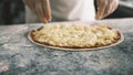 Close up for cook& x27;s hands putting cheese on the pizza Four Cheeses.Chef adding the ingredients to the pizza Royalty Free Stock Photo