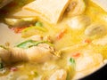 Close-up Cooking of Chicken Green Curry, adding Fresh Green Thai Eggplant, Chili and Basil into boiling curry in pan. Local Thai