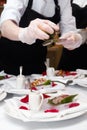 Close-up of cooking a dish of fillet of meat and sauce in a round white plate by a waiter in a restaurant before a romantic dinner