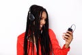 Close up cool young african woman listening music with mobile phone and headphones on white background Royalty Free Stock Photo