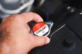 Mechanic hand opens car radiator cap to inspect and add coolant in a car engine compartment. Royalty Free Stock Photo