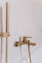 Close-up of a copper bathroom faucet installed on a tiled wall adjacent to a shower cubicle