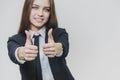 Female hand gestures thumbs up. Business girl is smiling broadly and shares positive emotions. Focus on the thumbs