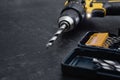 Close-up of a cordless electric drill with a metal drill bit and set of bits in a toolbox on a dark background. Concept for Royalty Free Stock Photo