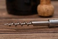 Close-up of corkscrew on table, oak cork and bottle of wine on background Royalty Free Stock Photo