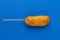 Close-up of corn dog with mustered sauce over skewer on blue background with copy space