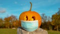 CLOSE UP: Corona conscious orange Halloween pumpkin wearing medical face mask Royalty Free Stock Photo