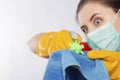 Close-up of a coronavirus model in the hands of a cleaning lady. A housewife in a mask and gloves holds a atomizer and rag.