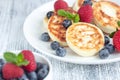 Close up of cottage cheese pancakes with fresh berries on white wooden table. Tasty breakfast food. Syrniki