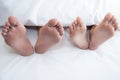 Close up of couple barefoot under blanket in bedroom in honeymoon vacation holiday in long weekend at home. Relaxation of sexual