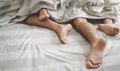 Close up couple feet having sex in bed - Young lovers intimate and passionate moments under white sheets in bedroom Royalty Free Stock Photo