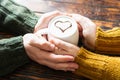 Couple holding hands around a mug of coffee with a cocoa heart on milk foam