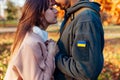 Close up of couple holding hands. Sad woman hugging husband in ukrainian military uniform with flag chevron. Royalty Free Stock Photo
