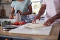 Close Up Of Couple In Kitchen At Home Preparing Homemade Pizzas Together