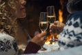 Close up of couple in love clinking with champagne flutes during christmas holiday celebration. Fireplace in background. Winter Royalty Free Stock Photo