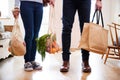 Close Up Of Couple Returning Home From Shopping Trip Carrying Groceries In Plastic Free Bags