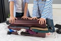Close up couple trying to close overfilled suitcase on bed, holiday travel concept Royalty Free Stock Photo