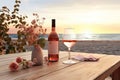 Close up of couple wine champagne glasses and bottle for celebration on wooden table with sea view and sunset sky background, Royalty Free Stock Photo