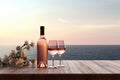 Close up of couple wine champagne glasses and bottle for celebration on wooden table with sea view and sunset sky background, Royalty Free Stock Photo