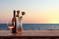 Close up of couple wine champagne glasses and bottle for celebration on wooden table with sea view and sunset sky background, Royalty Free Stock Photo