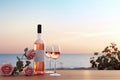 Close up of couple wine champagne glasses and bottle for celebration on wooden table with sea view and sunset sky background, Royalty Free Stock Photo