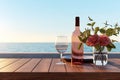 Close up of couple wine champagne glasses and bottle for celebration on wooden table with sea view and sunset sky background, Royalty Free Stock Photo