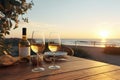 Close up of couple wine champagne glasses and bottle for celebration on wooden table with sea view and sunset sky background,