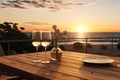 Close up of couple wine champagne glasses and bottle for celebration on wooden table with sea view and sunset sky background, Royalty Free Stock Photo