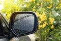 Close up on the cover plastic of mirror wing of car with on the glass with drop of water rain.