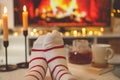 Photo of feet in striped socks on side table with candles, teapot and cup  bevor fireplace Royalty Free Stock Photo