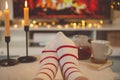 Photo of feet in striped socks on side table with candles, teapot and cup  bevor fireplace Royalty Free Stock Photo