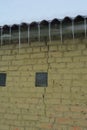 A close up of a crack on a brick wall near the roof without a roof gutter with icicles hanging. Repairing brick wall cracks Royalty Free Stock Photo