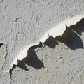 Close-up of a cracked and peeling painted wall. The surface shows both smooth white Royalty Free Stock Photo