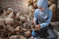 close up of craftswoman in veil weaving water hyacinth crafts