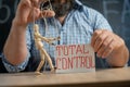 Close-up of a crafty puppet in the hands of a conspiracy theorist man sitting at the table. Man controls people and