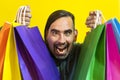 Close-up of a crazy man holding colorful shopping bags over yellow background.  Shopping Concept Royalty Free Stock Photo