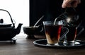 A close up of cream being poured into steaming hot tea against a dark background with light coming from behind. Royalty Free Stock Photo