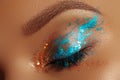 Close-up Creative art make-up. Cream Texture design on female Eye Lid. Makeup with aquamarine paint and bronze pigment