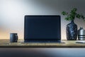 Close up of creative dark designer desktop with empty laptop screen, coffee cup, supplies and other items on concrete wall Royalty Free Stock Photo