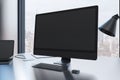 Close up of creative designer desk top with empty black mock up computer monitor laptop and supplies in modern office with window Royalty Free Stock Photo
