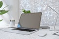 Close up of creative designer desktop with empty laptop screen, lamp, supplies various other objects and shiny light tile wall Royalty Free Stock Photo