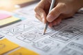 Close-up of a Creative Designer Hand Sketching User Interface Wireframes and Mobile App Layouts with a Pencil on Paper featuring Royalty Free Stock Photo