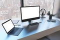 Close up of creative designer table with empty white mock up computer monitor laptop and supplies in modern office with window and Royalty Free Stock Photo