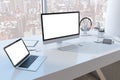 Close up of creative desktop with empty white mock up computer monitor laptop and supplies in modern office with window and