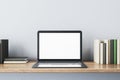 Close up of creative designer desk with books and empty white mock up laptop screen on white concrete wall. 3D Rendering Royalty Free Stock Photo