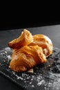 Close-up of croissants on a dark background. One croissant broken into pieces