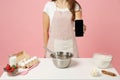 Close up cropped chef cook confectioner or baker in white t-shirt cooking cake or cupcake at table hold using mobile