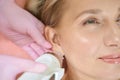 Close up of cosmetologist doing microneedle rf lifting of ear skin of woman