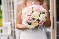 Close-up of a cropped frame, the bride in a white dress is holding her wedding bouquet of peonies, showing flowers to Royalty Free Stock Photo