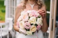Close-up of a cropped frame, the bride in a white dress is holding her wedding bouquet of peonies, showing flowers to Royalty Free Stock Photo